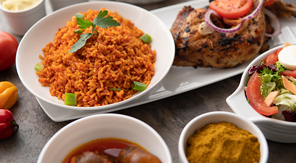 an arrangement of Nigerian foods from jollof rice to fried chicken services on ceramic white plates
